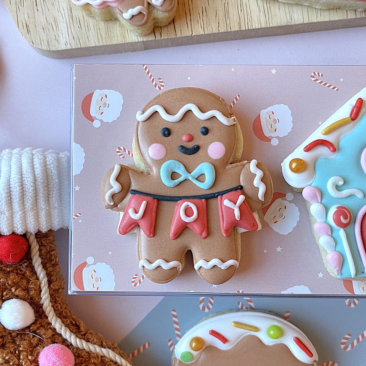 Mini christmas gingerbread cookie with brown sugar glaze decorated with white icing pink cheeks and joy letters