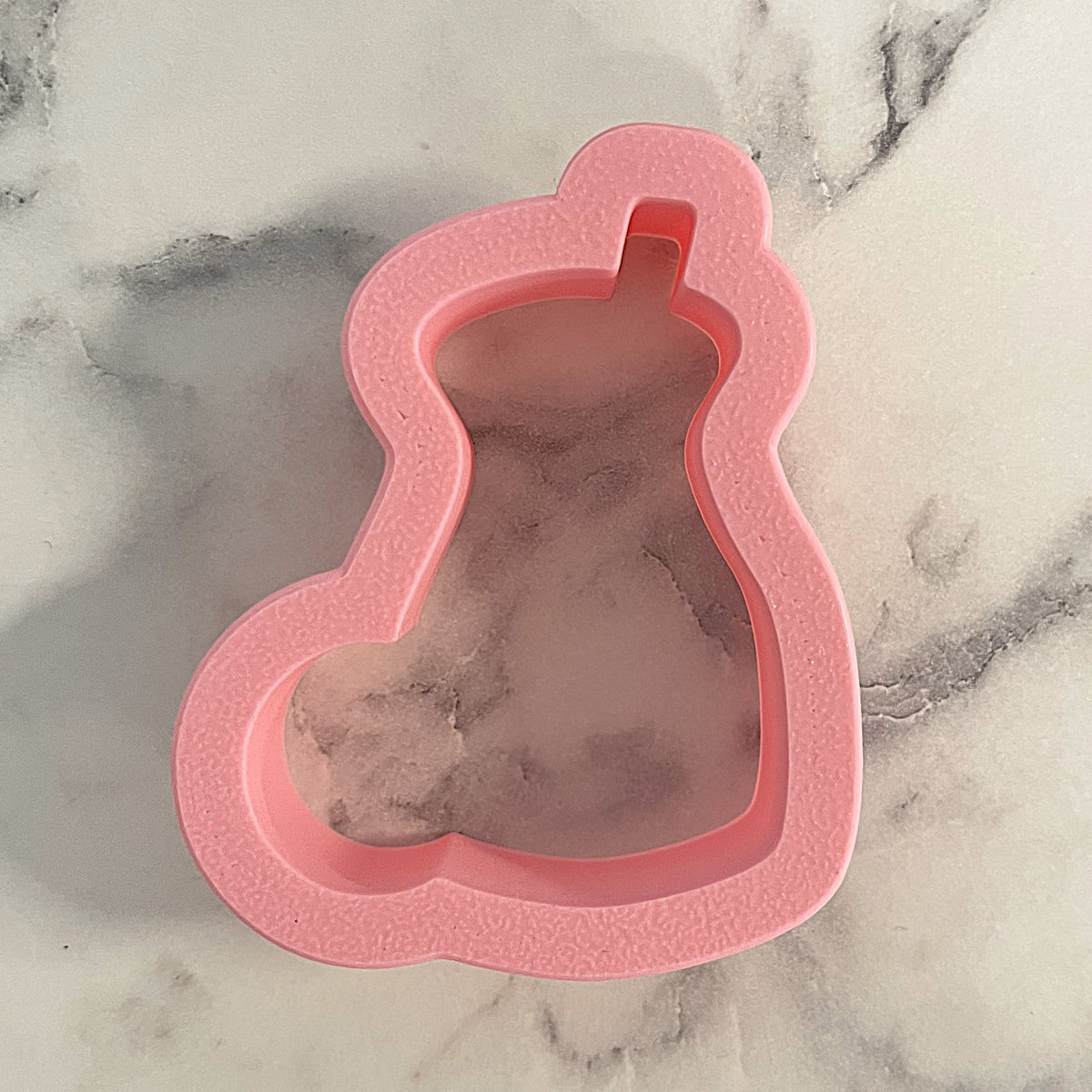 Pink silicone cookie cutter shaped like a dress form included with mini milk bottle set for baking use