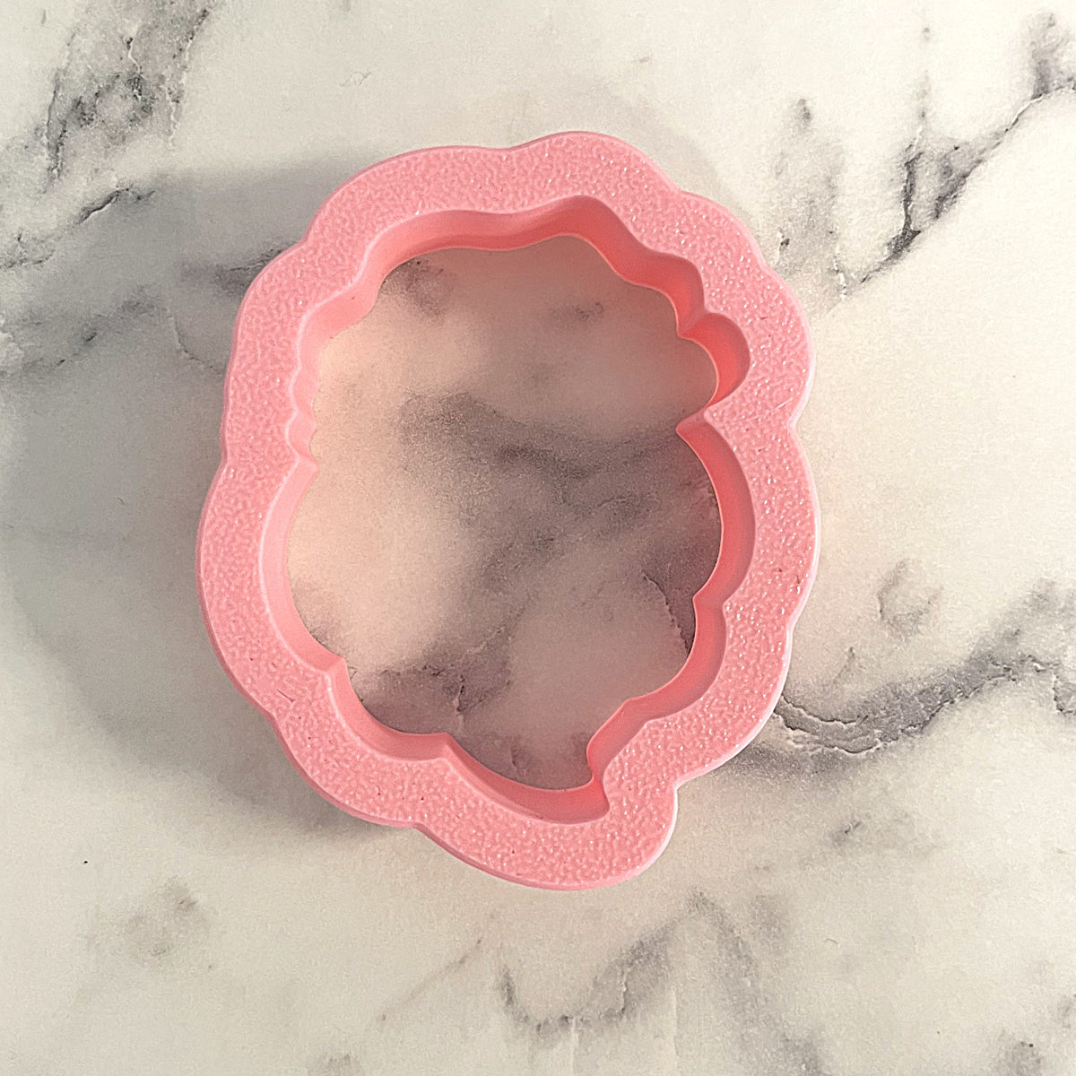 Pink silicone mini santa with full beard cookie cutter mold with scalloped edges and textured surface for bath bombs