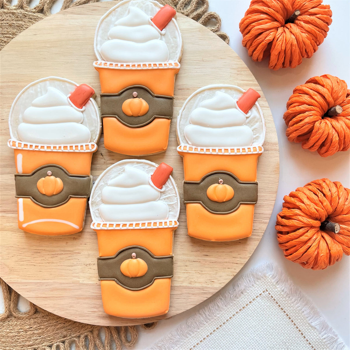Four orange and white frosted pumpkin spiced latte cookies with brown bands and red straws from fall coffee date cookie cutter bundle