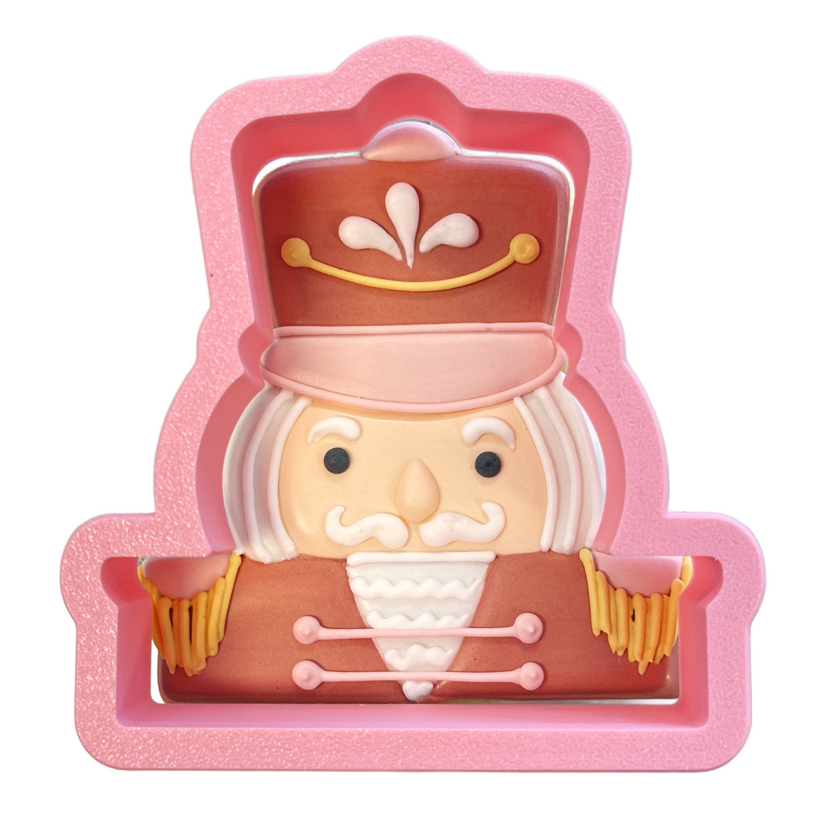 Pink silicone nutcracker face cookie cutter with brown hat beige face white mustache and uniform detailed features