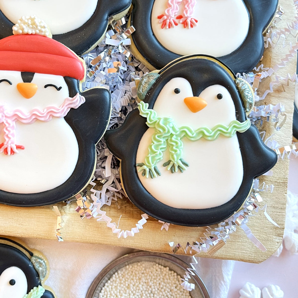 Penguin with earmuffs flour box club cookie cutter shaped black and white sugar cookies decorated with colorful scarves and glitter