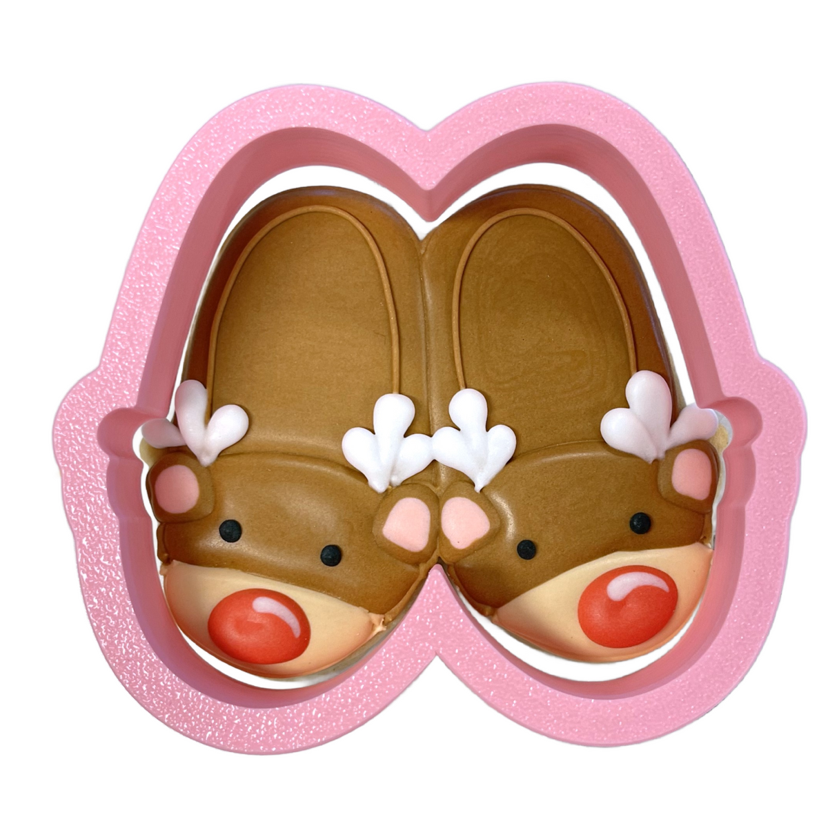Pink heart-shaped cookie cutter holding brown reindeer slippers with white antlers pink cheeks and red noses