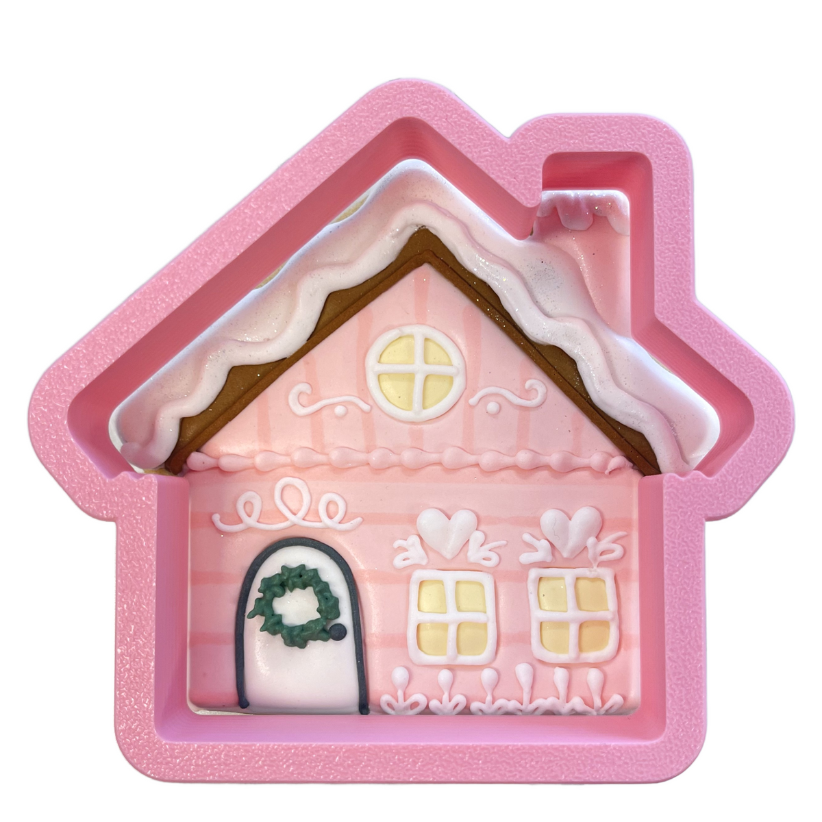 Pink glittery silicone snowy cabin flour box club cookie cutter with white icing details green wreath and yellow windows