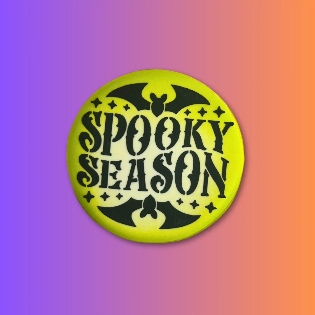 Bright yellow circular stencil button with black spooky season text featuring bat and star designs for halloween crafts