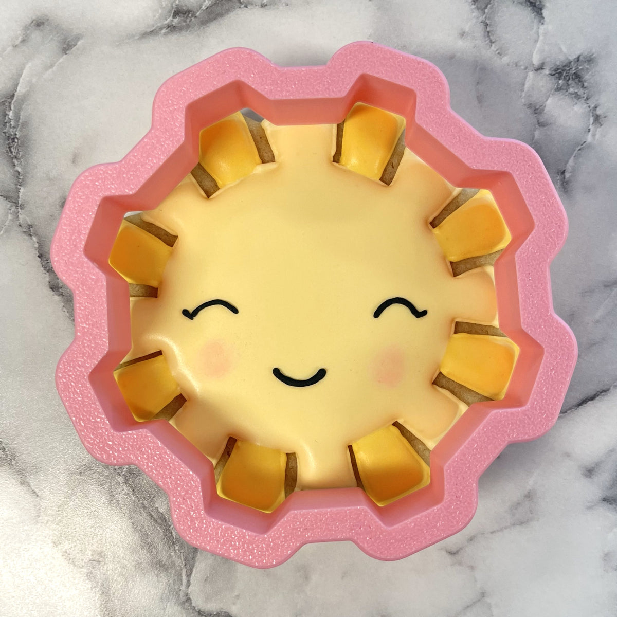 Sunshine cookie cutter sun-shaped silicone baking mold in pink and yellow with smiling face design