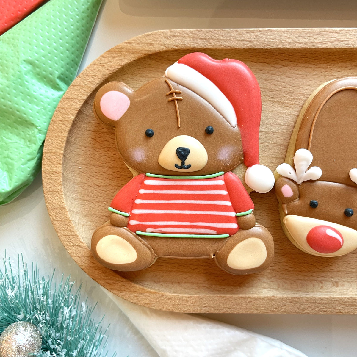 Chocolate-colored gingerbread bear cookie wearing a red and white santa hat and striped sweater from christmas pajamas cookie cutter bundle