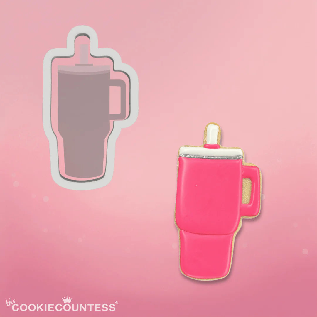 A vibrant pink cookie shaped like a travel mug with a silver rim and white lid from trendy tumbler cookie cutter