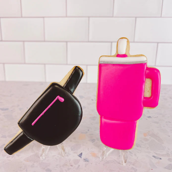 Bright pink frosted cookie shaped like a beverage mug with white rim and handle for belt bag cookie cutter