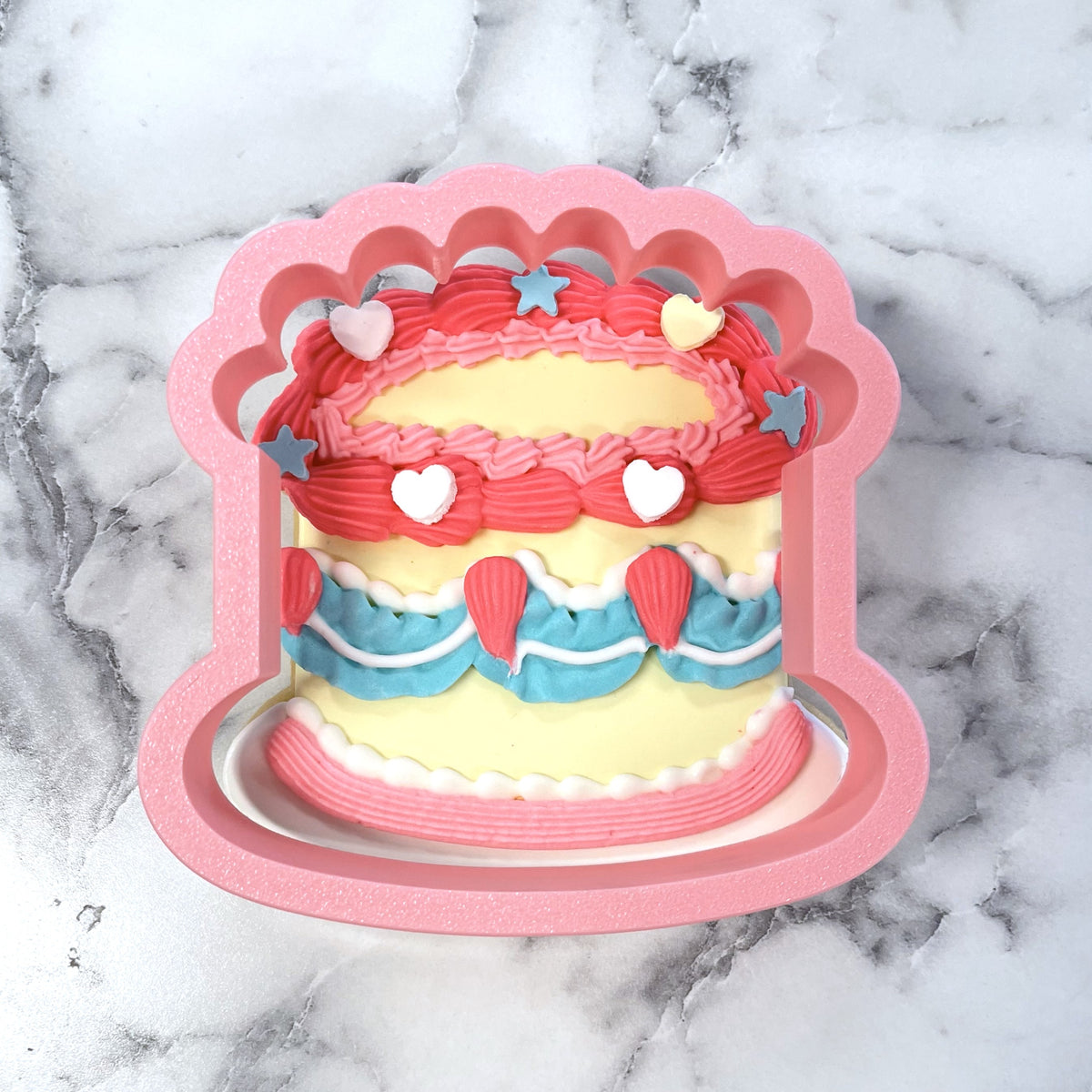 A pink silicone vintage birthday cake flour box club cookie cutter shaped like a layered cake with colorful decorations