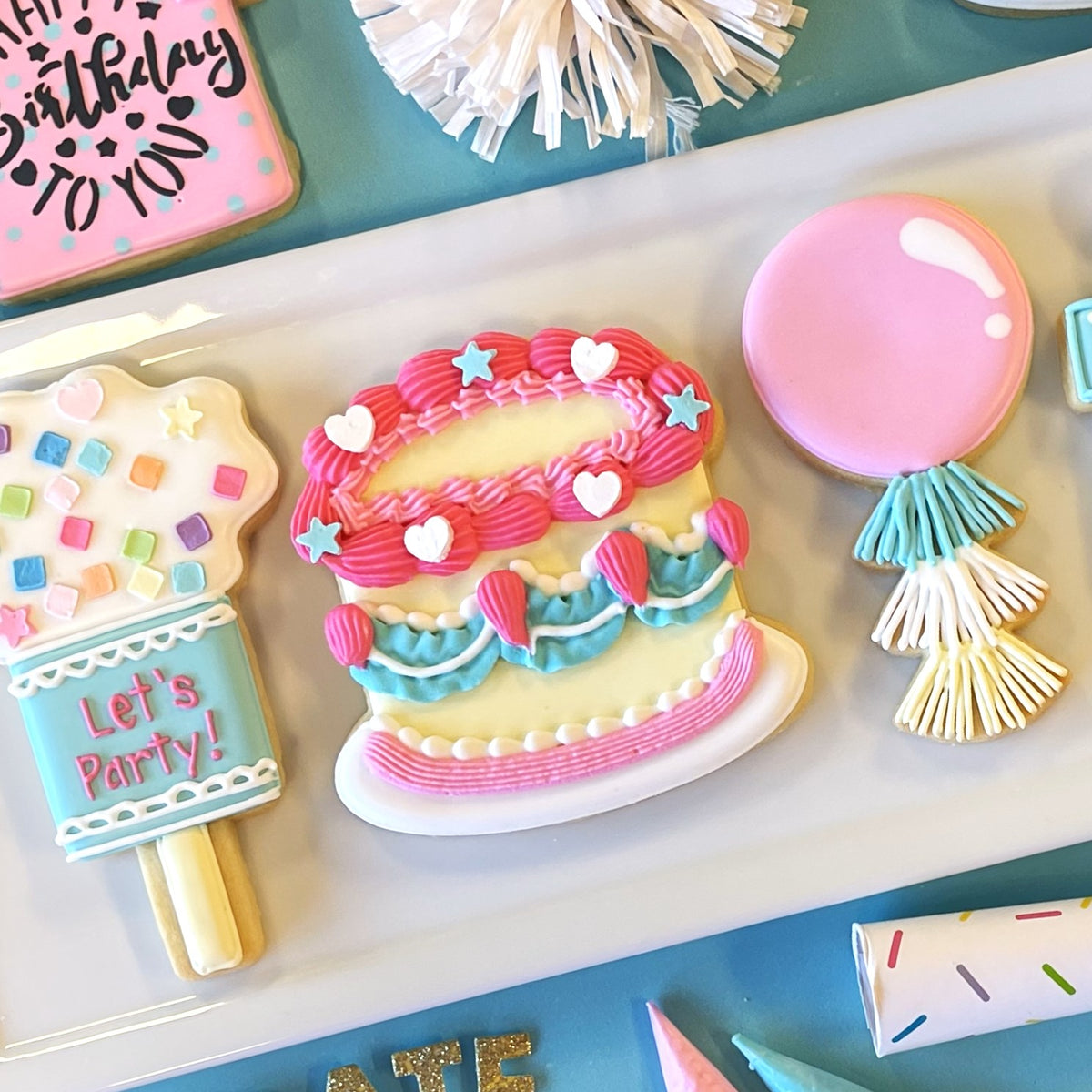 Vintage birthday cake flour box club cookie cutter shaped colorful two-tiered cookie with pink blue frosting swirls and hearts