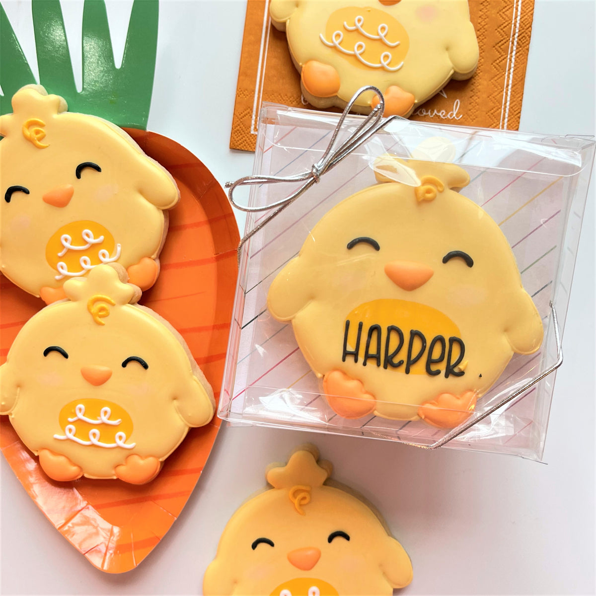 Yellow chick-shaped cookies with white icing and harper name made using round chick cookie cutter design