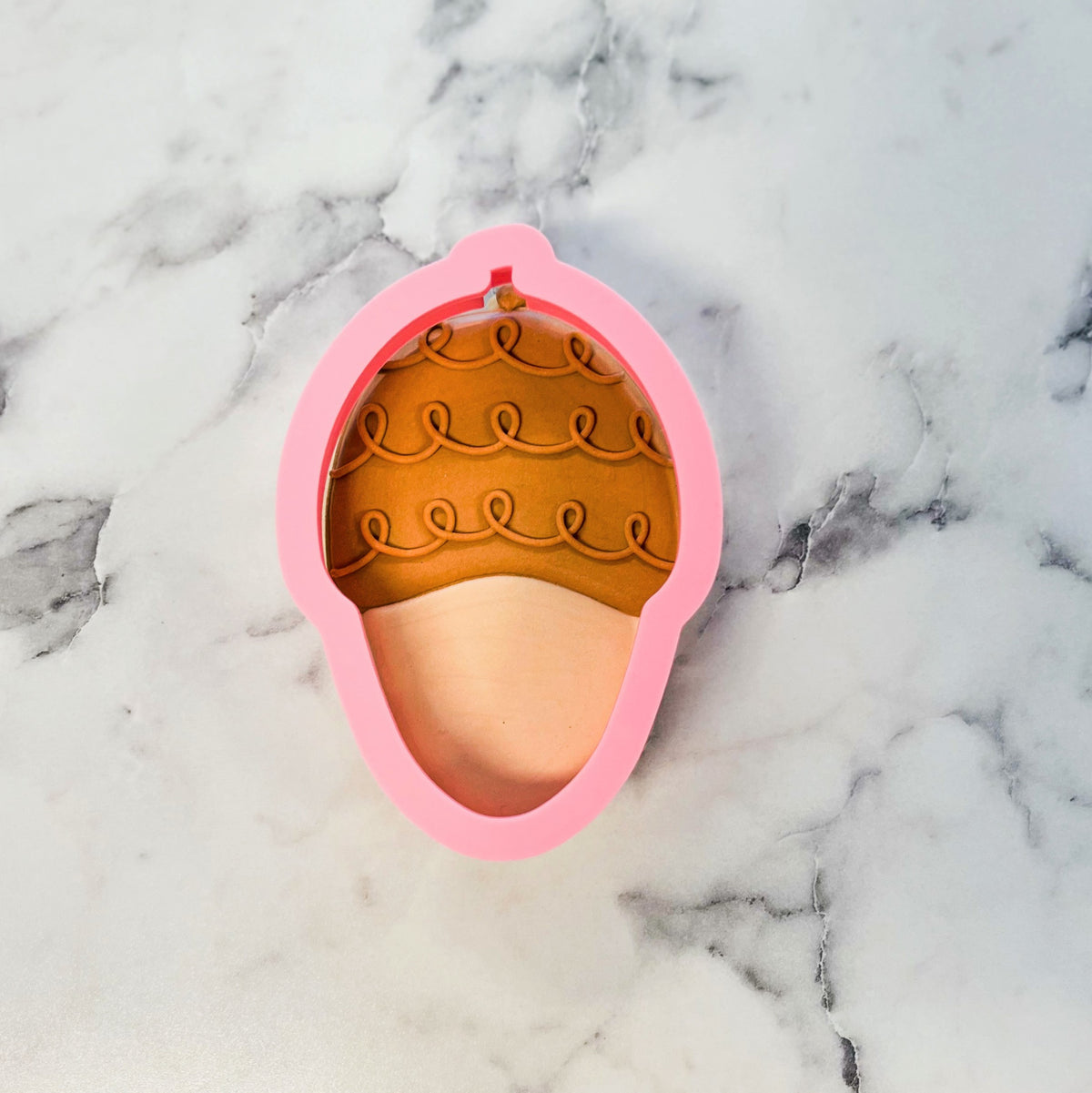 Pink silicone acorn doodle cookie cutter with brown scalloped top and beige bottom for baking and crafts