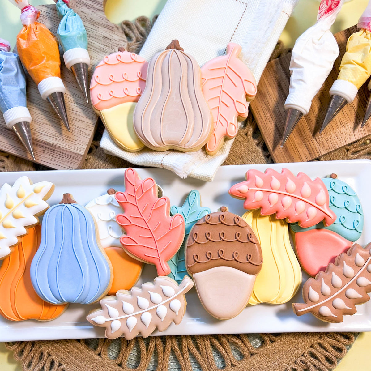 Autumn-themed sugar cookies shaped with pastel acorn doodle cookie cutter in pink blue orange and beige hues