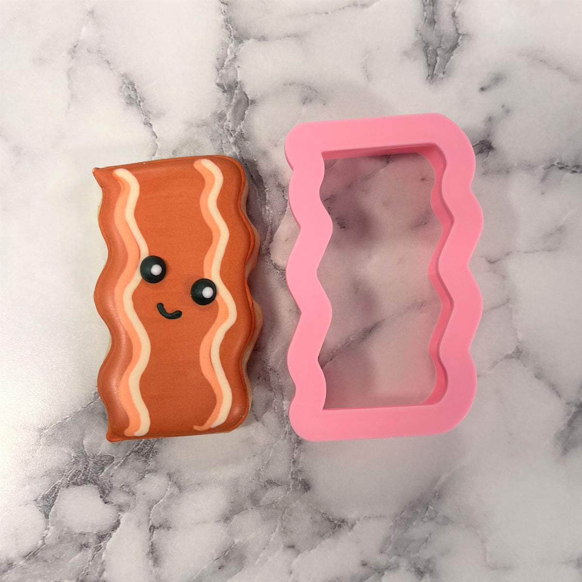 Mini bacon cookie cutter is a cute orange silicone squishy shaped like bacon with white stripes and a smiling face