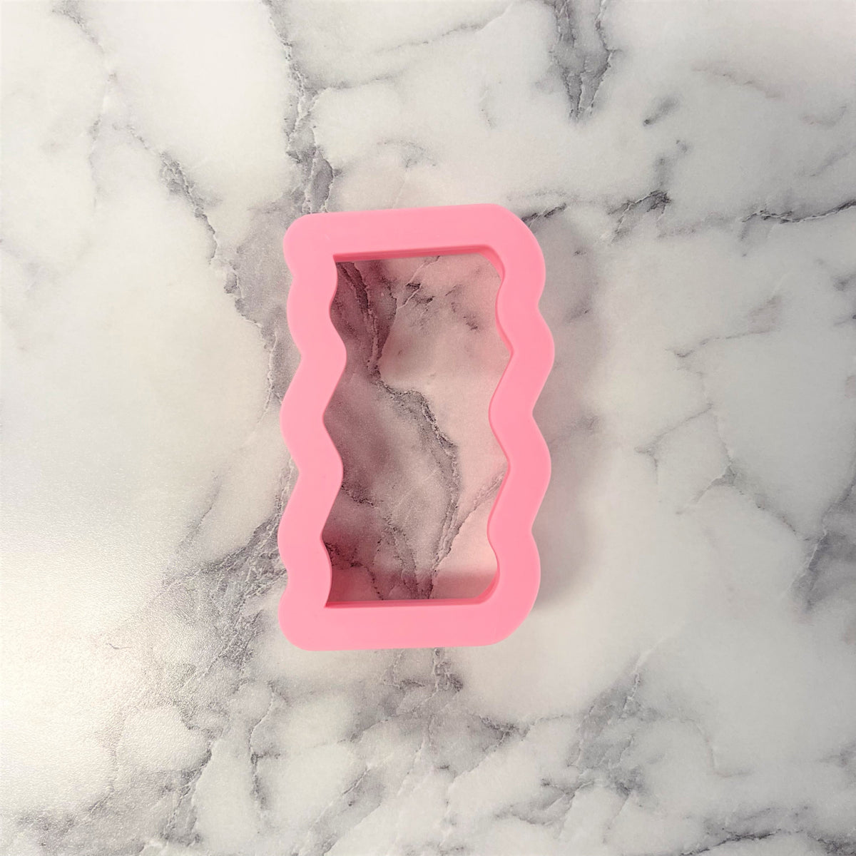 Pink silicone bacon cookie cutter mold with wavy rectangular outline for baking and shaping cookies