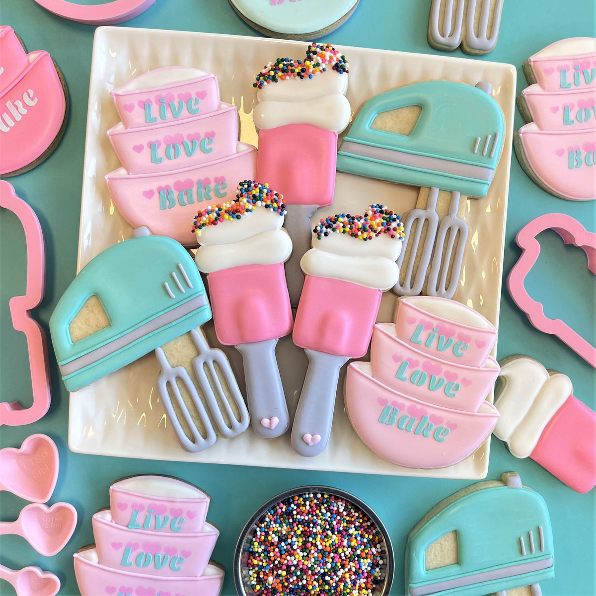 Pastel pink and mint green sugar cookies shaped like kitchen appliances decorated with white icing and colorful sprinkles using stacked bowls cookie cutter