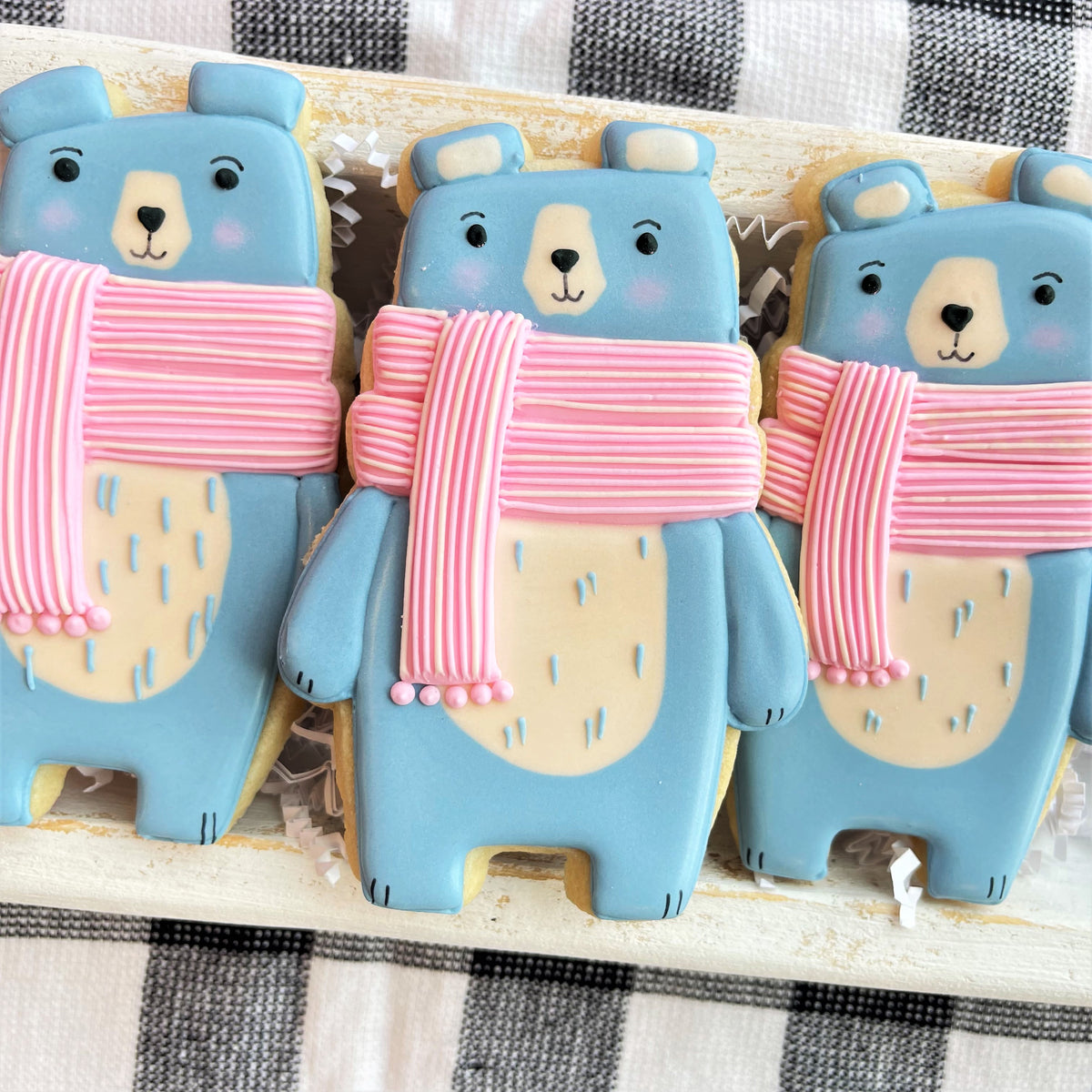 Blue bear-shaped cookies with pink striped scarves and beige accents made using cute woodland animals cookie cutter set