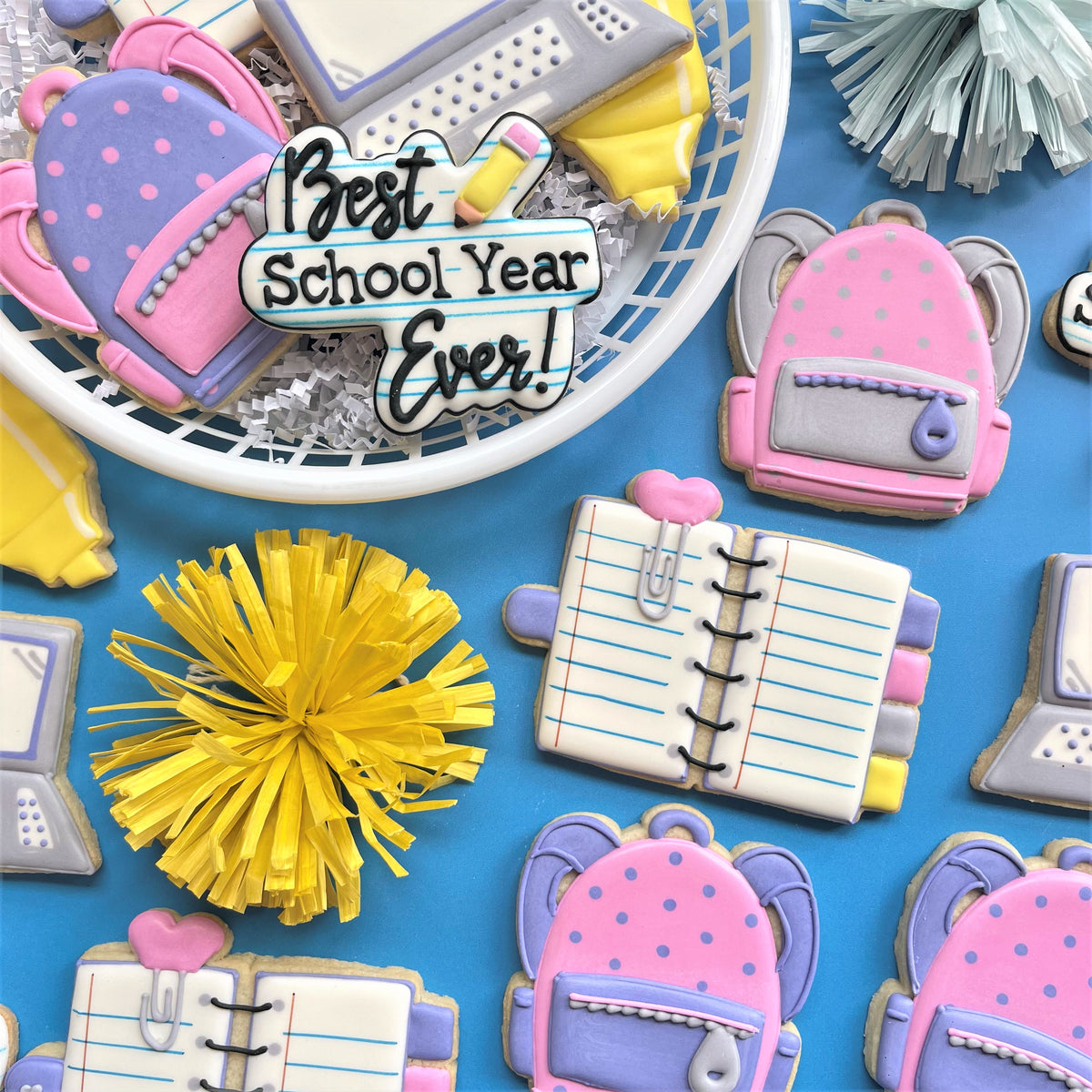 Pink and purple polka-dotted backpack-shaped sugar cookie with gray straps and silver zipper made using best school year ever plaque cookie cutter
