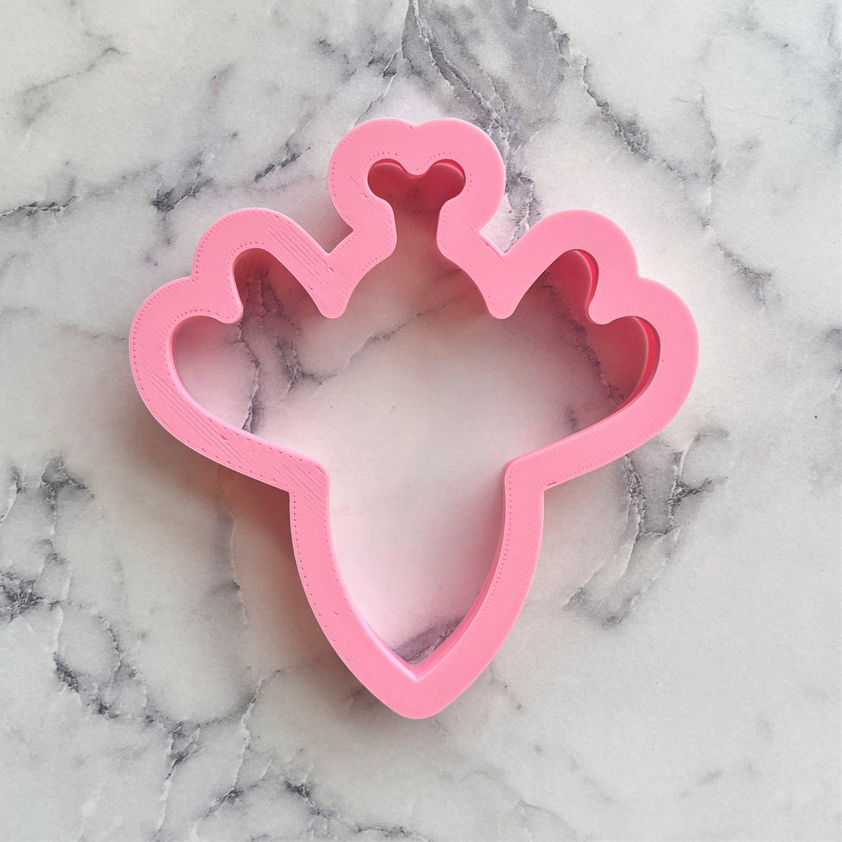 Pink plastic princess crown cookie cutter with heart-shaped points and smooth glossy finish for bumblebee cookies
