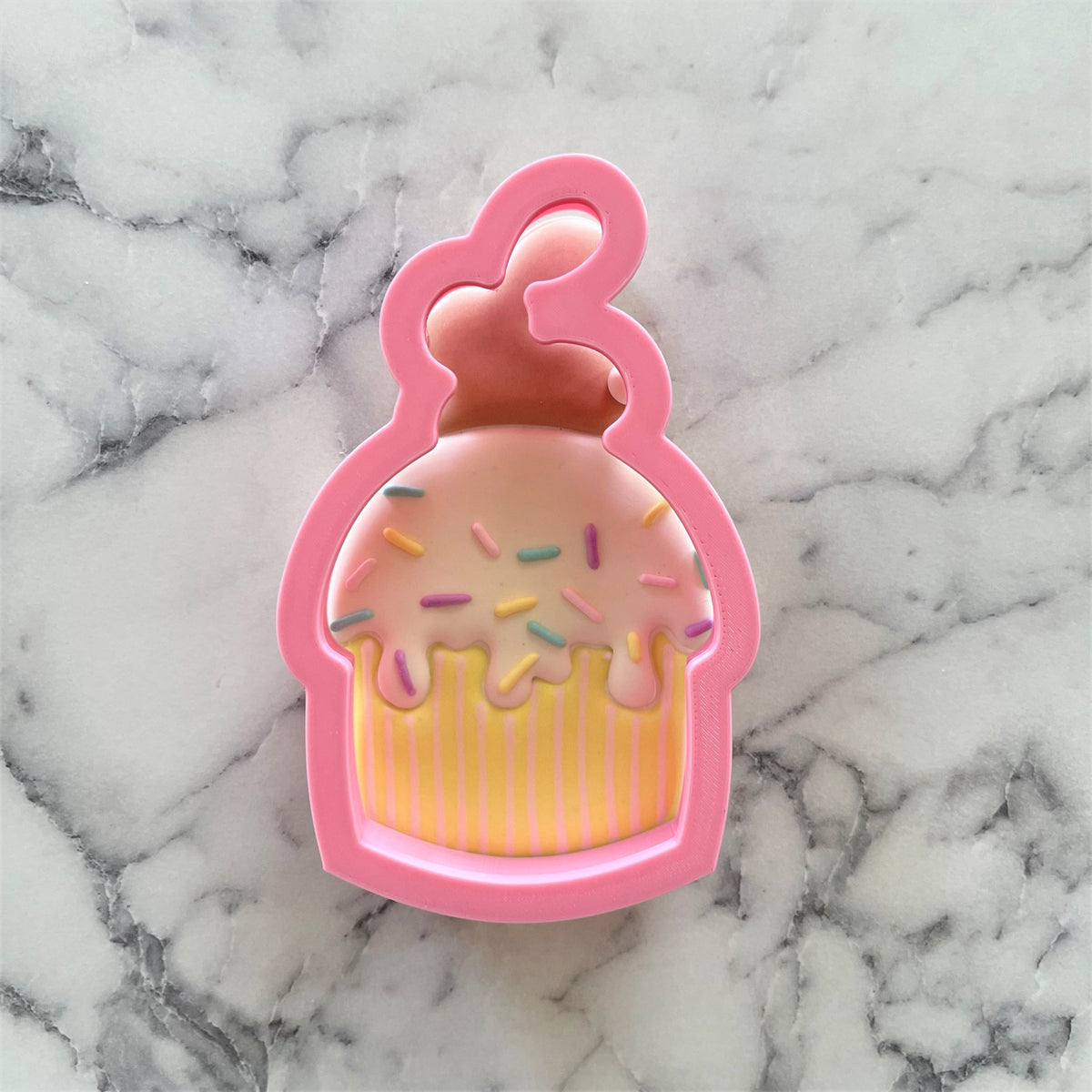 Pink silicone bunny muffin cookie cutter with colorful sprinkles and striped yellow icing on cupcakes
