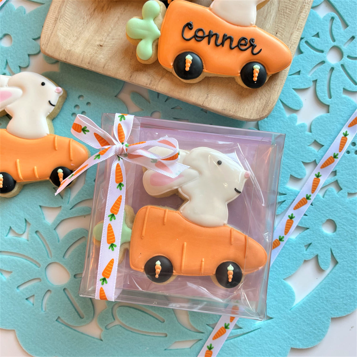 Bunny in carrot car cookie cutter shaped white bunny driving orange carrot cookie with black wheels and icing details