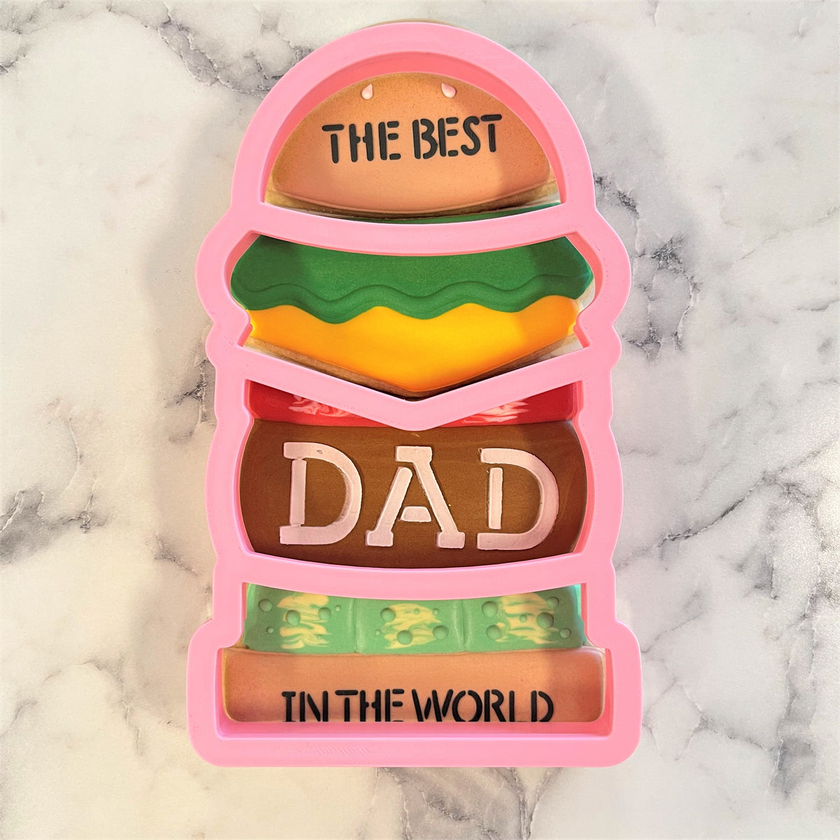 Pink silicone burger-shaped 4-in-1 multi-cookie cutter with layered design and the best dad in the world text