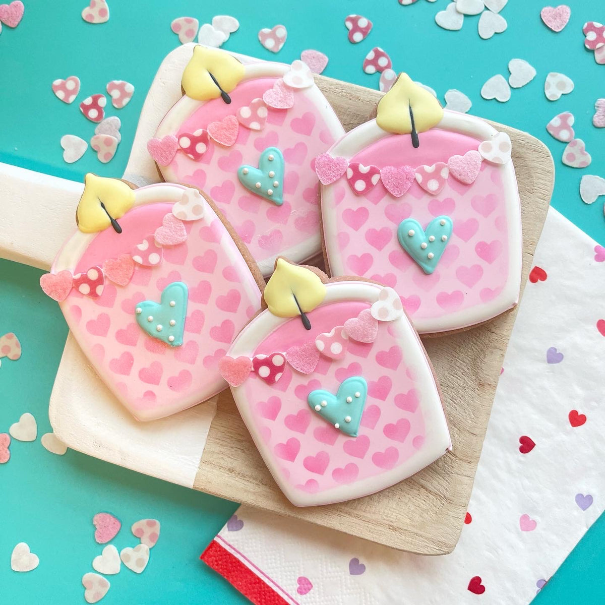 Pink heart-patterned sugar cookies shaped like candles with yellow fondant flames made using candle glass jar cookie cutter