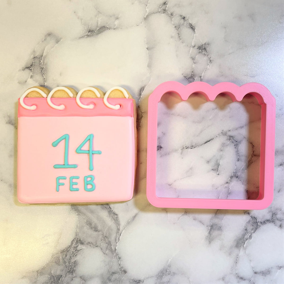 Pink calendar cookie with teal icing numbers and white decorative rings made using calendar cookie cutter