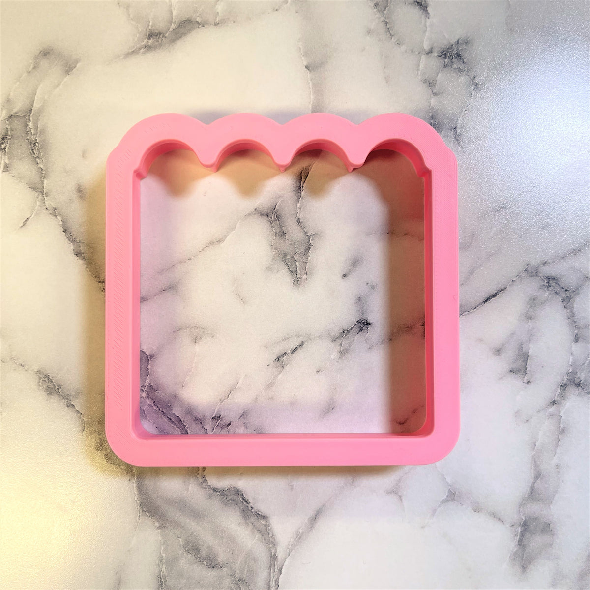 Pink silicone calendar cookie cutter mold with scalloped top edge and square shape for baking use
