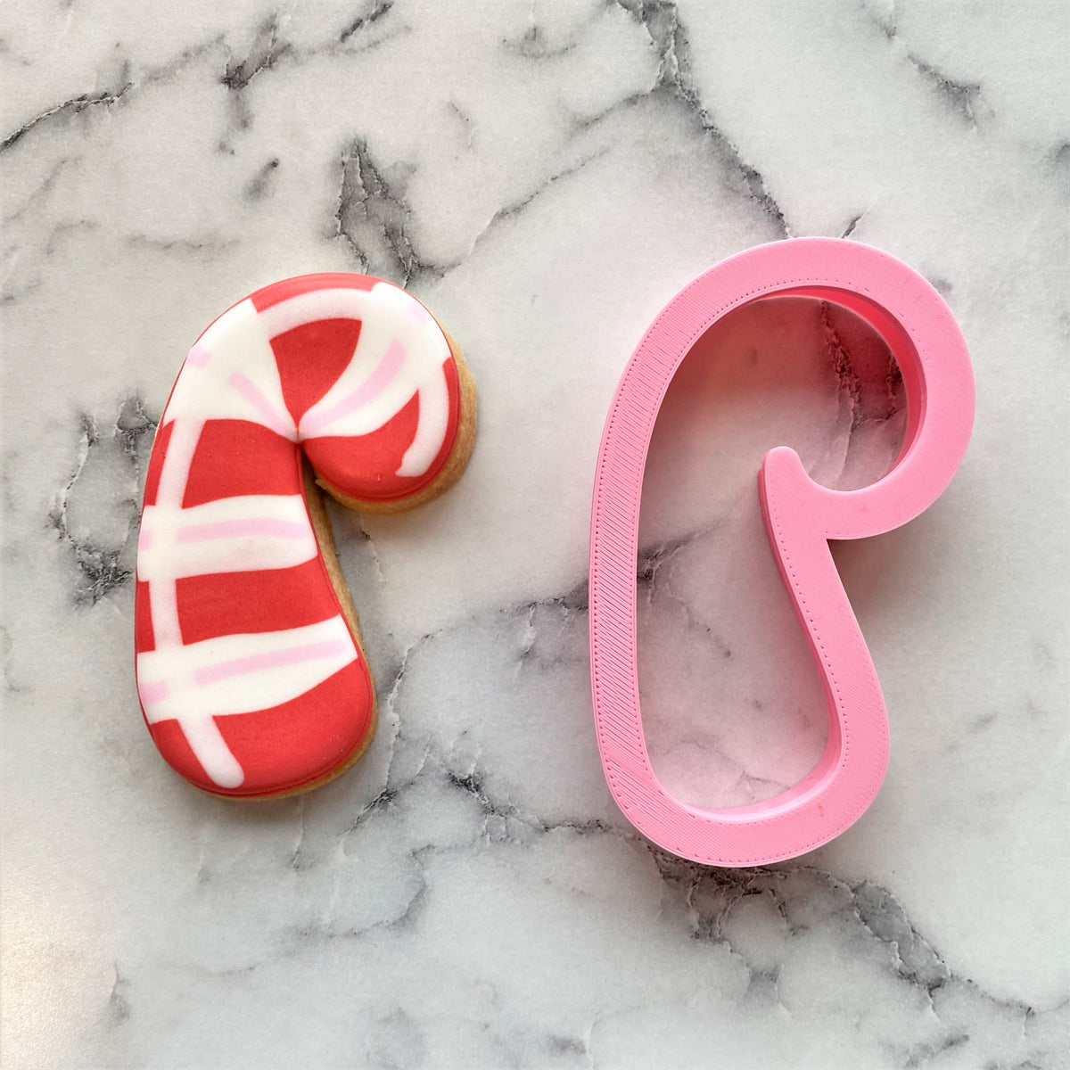 Pink candy cane rounded cookie cutter made of metal for festive holiday baking and cookie shaping