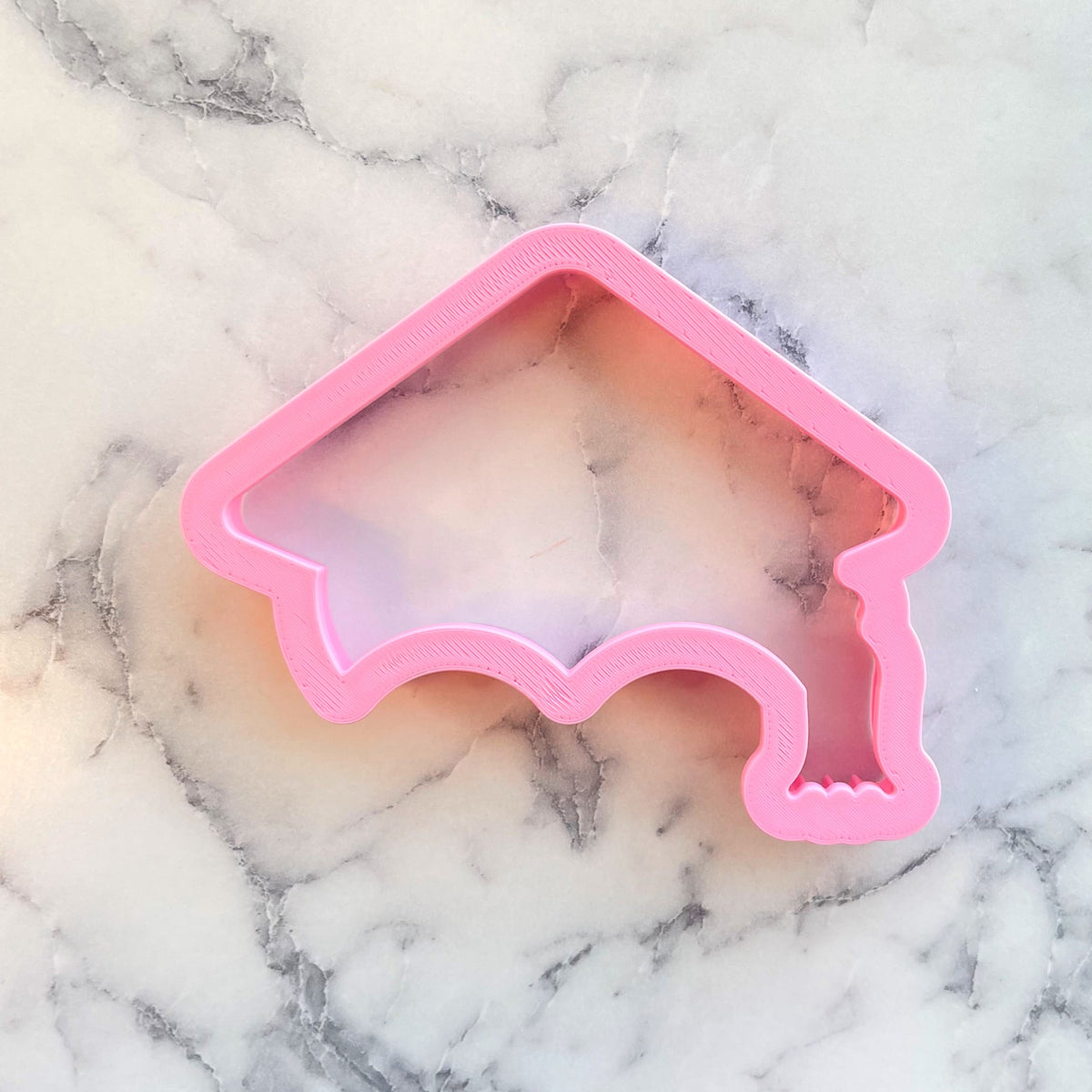 Pink plastic cap with tassel cookie cutter for graduation themed baking and decorating