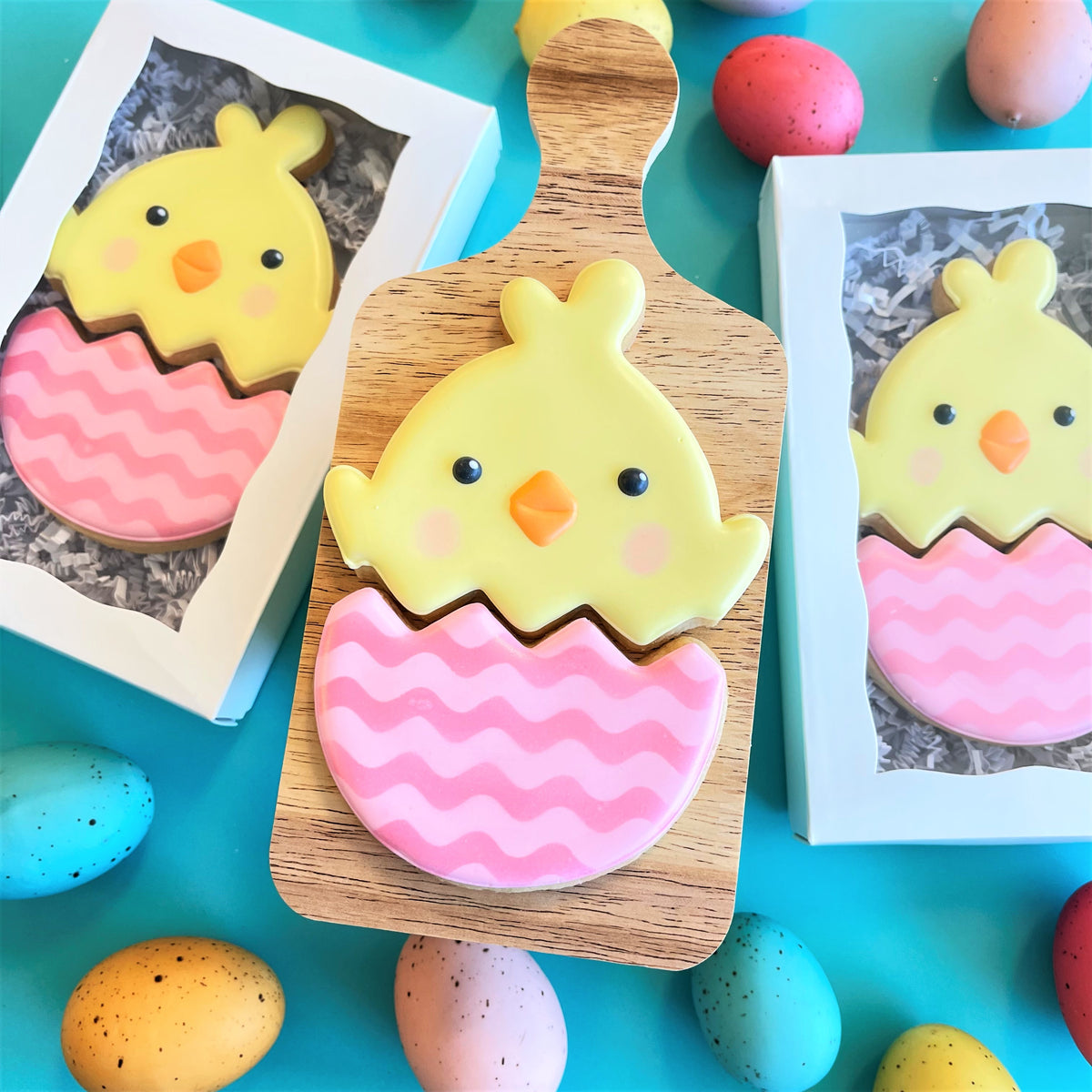 A yellow chick-shaped cookie with black eyes and orange beak sits atop a pink zigzag-patterned egg cookie made with chick in egg 2-in-1 multi-cookie cutter