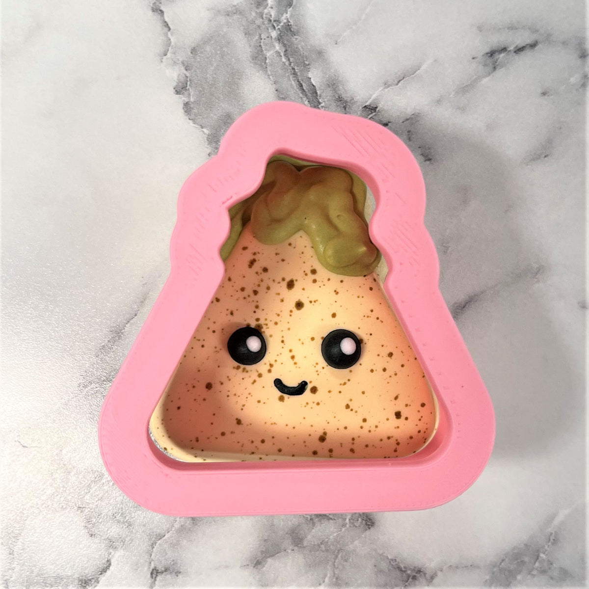 Pink silicone mini chip with guac cookie cutter shaped like a triangular rice cake with cute eyes and smiling mouth