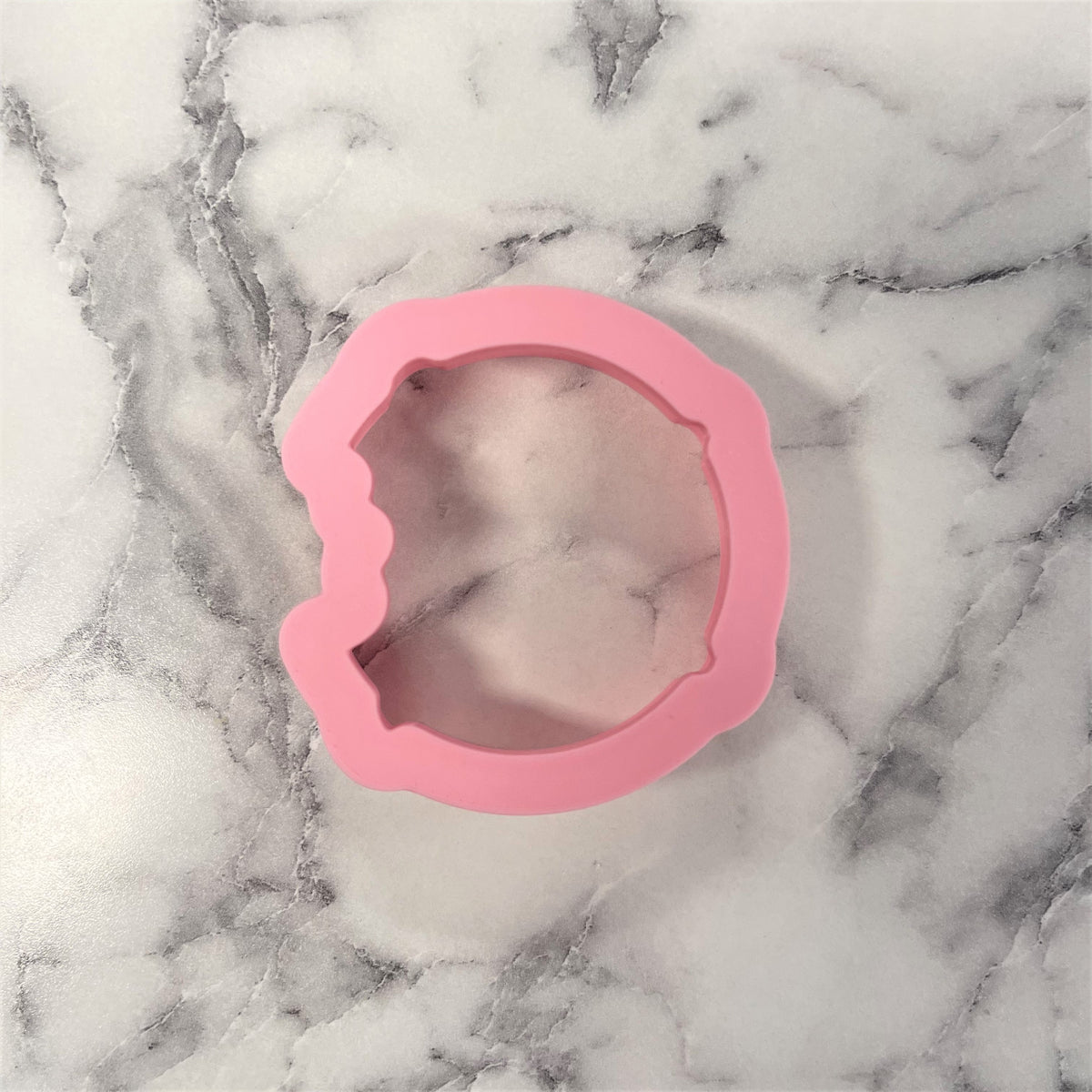 Pink silicone mini chocolate chip cookie cutter shaped like a donut with bite marks for baking use