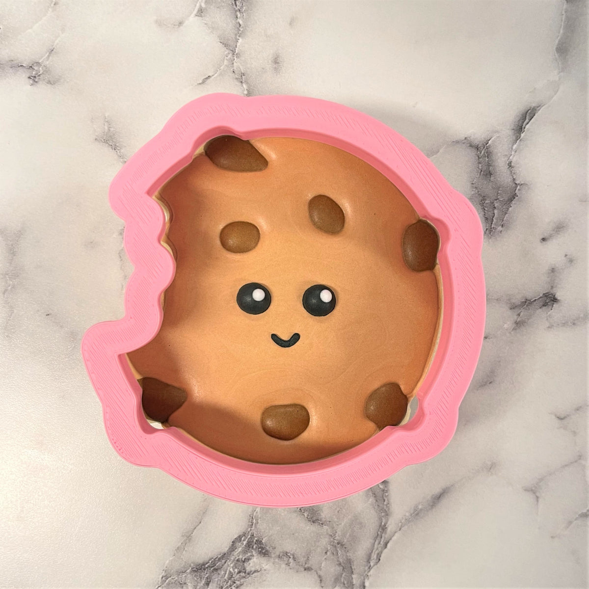 Pink silicone chocolate chip cookie cutter mold with cute face and chip details for baking fun cookies