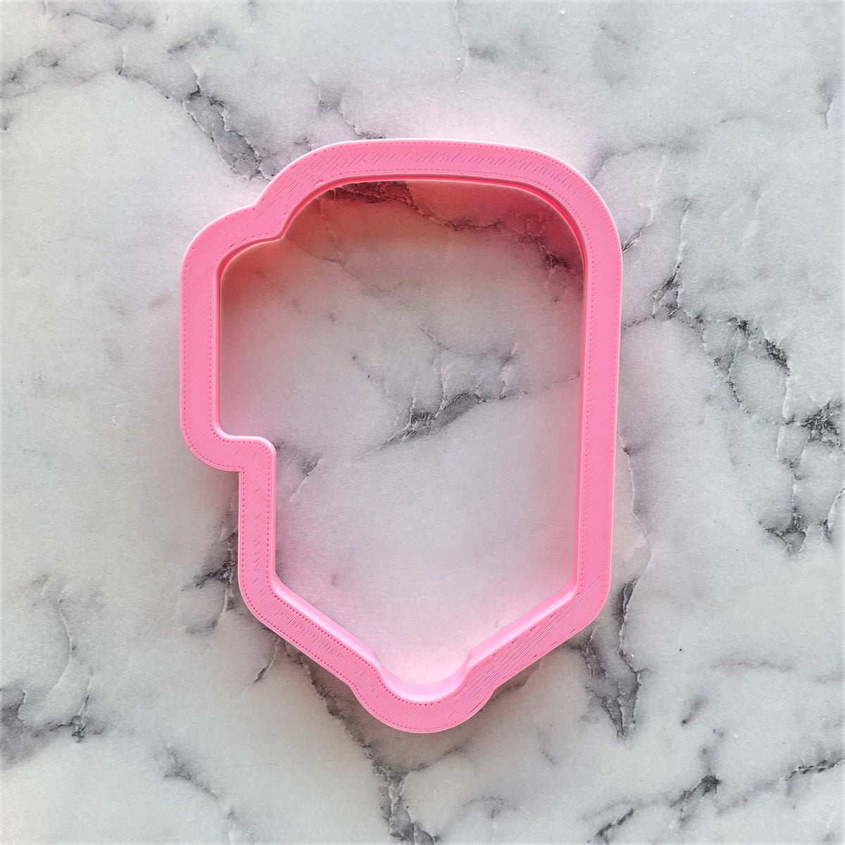 Pink plastic chubby xl pen cookie cutter shaped like a human head for baking and crafting use