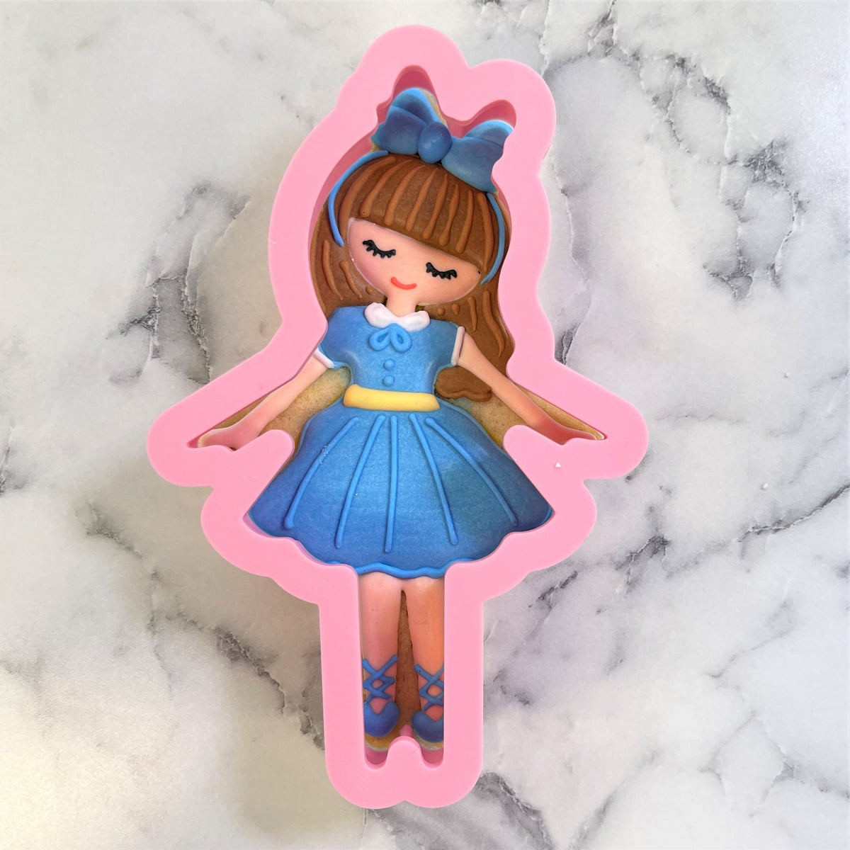 Pink silicone clara cookie cutter mold shaped like a cartoon girl in a blue dress with brown hair and bow