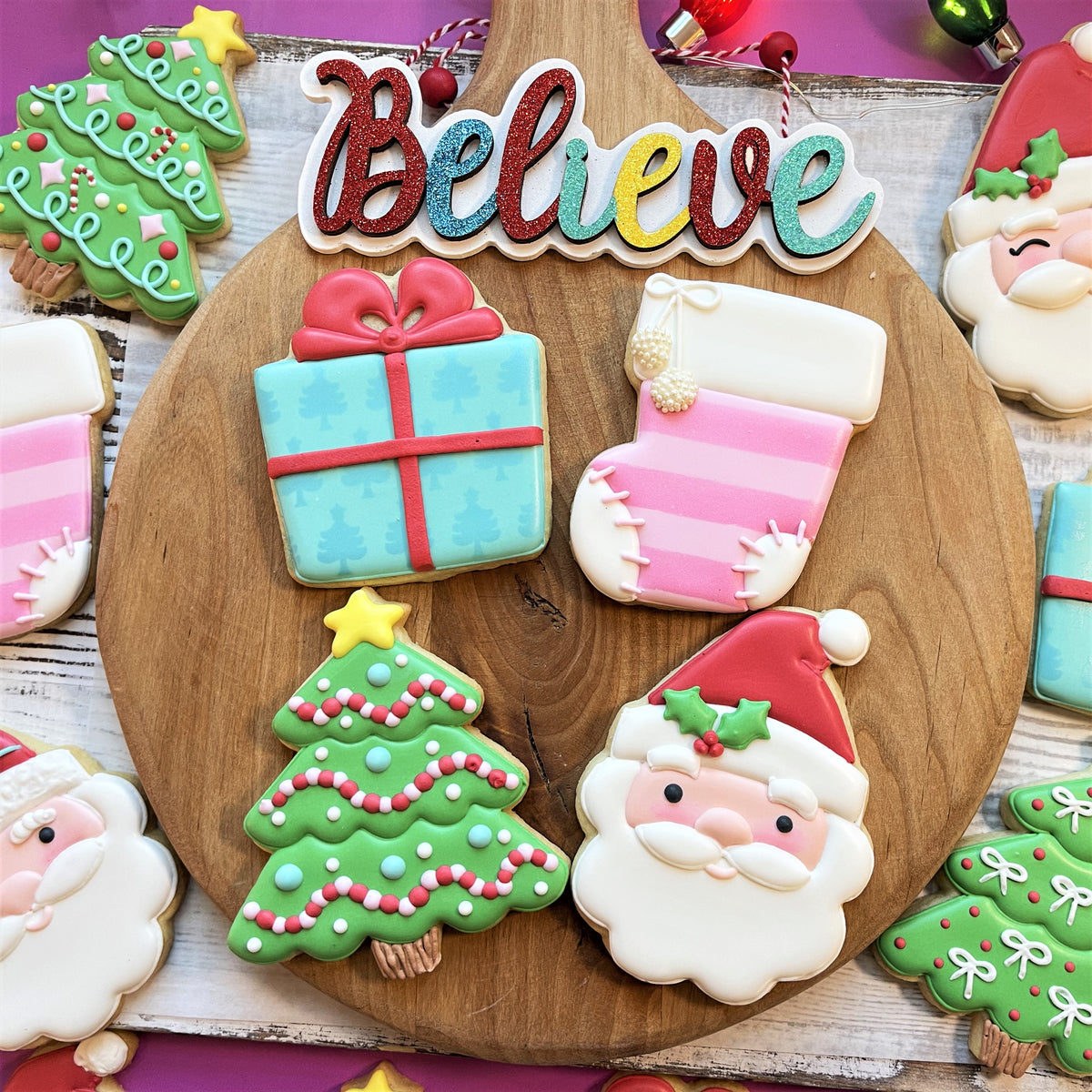 A festive glittery believe sign with rainbow letters and red bow featured with classic santa cookie cutter
