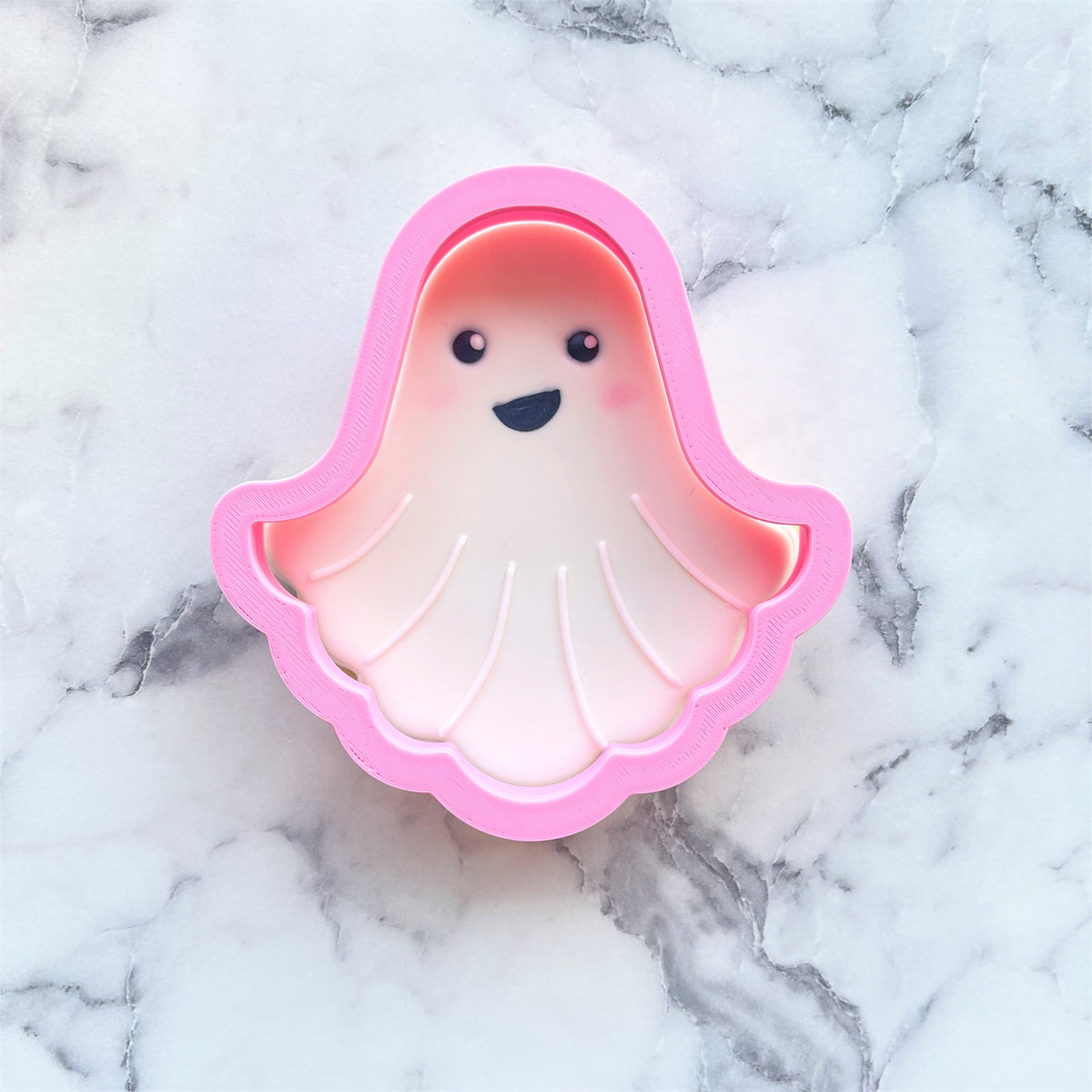 Pink plastic classic ghost cookie cutter with smiling face and shell-like design for baking and crafts