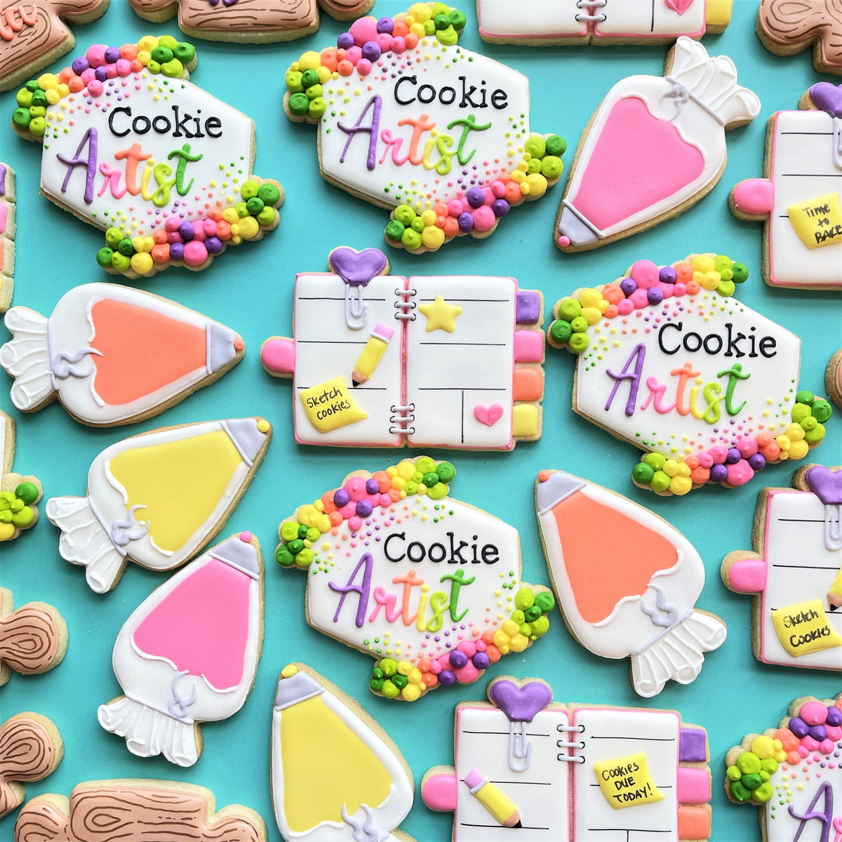 Colorful floral plaque cookie cutter with decorated sugar cookies shaped like pencils and notebooks with vibrant icing