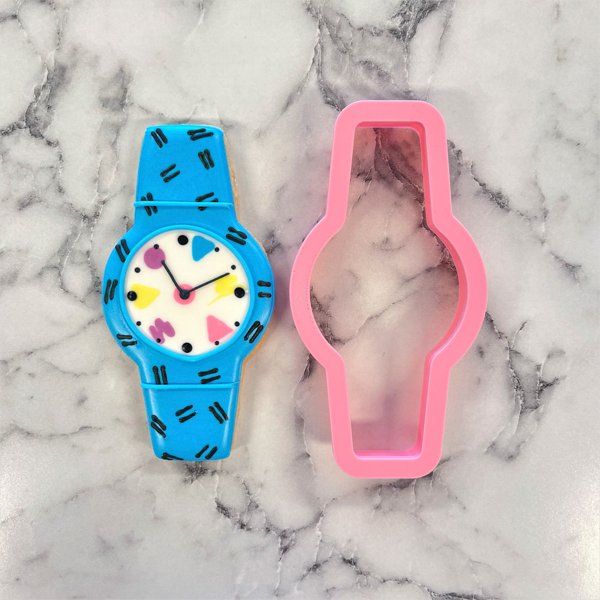 Bright blue plastic cool watch cookie cutter with white face featuring colorful geometric shapes and black markings