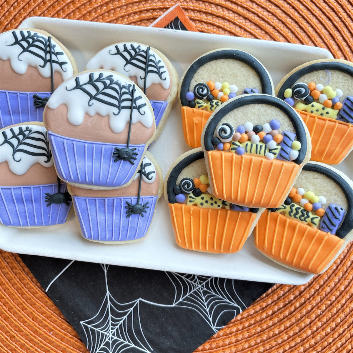 Mini cupcake cookie flip cutter cookie shaped like halloween cupcakes and baskets decorated with purple frosting black spiderwebs and sprinkles