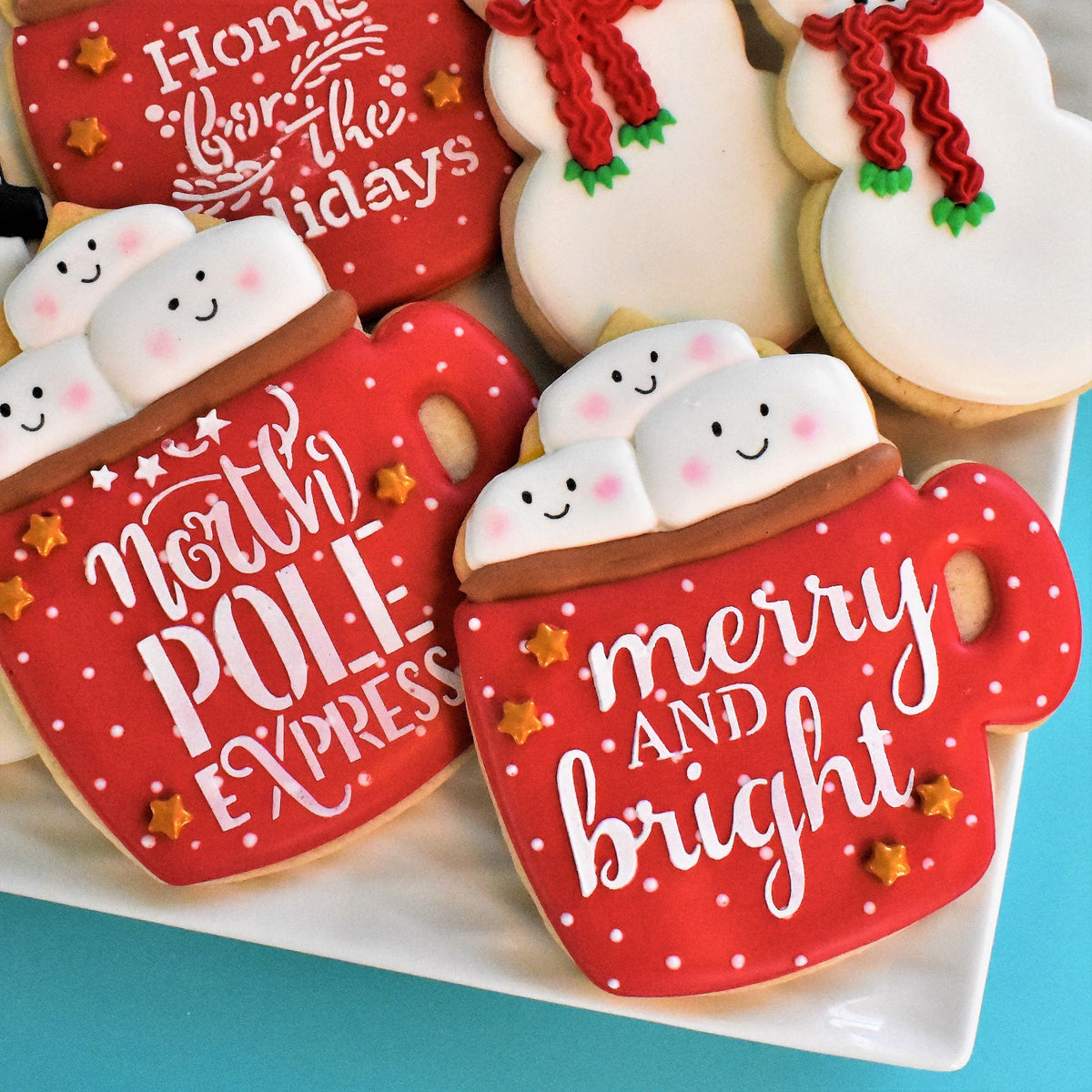 Red frosted holiday mug cookies decorated with white icing text and gold star sprinkles merry and bright kz stencil