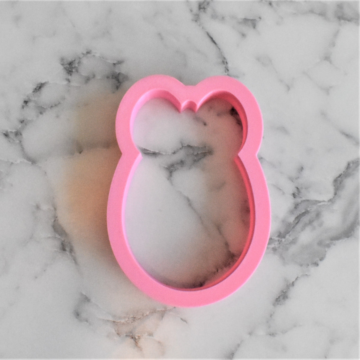 Pink silicone bunny-shaped egg with bow cookie cutter for making decorative cookies and treats