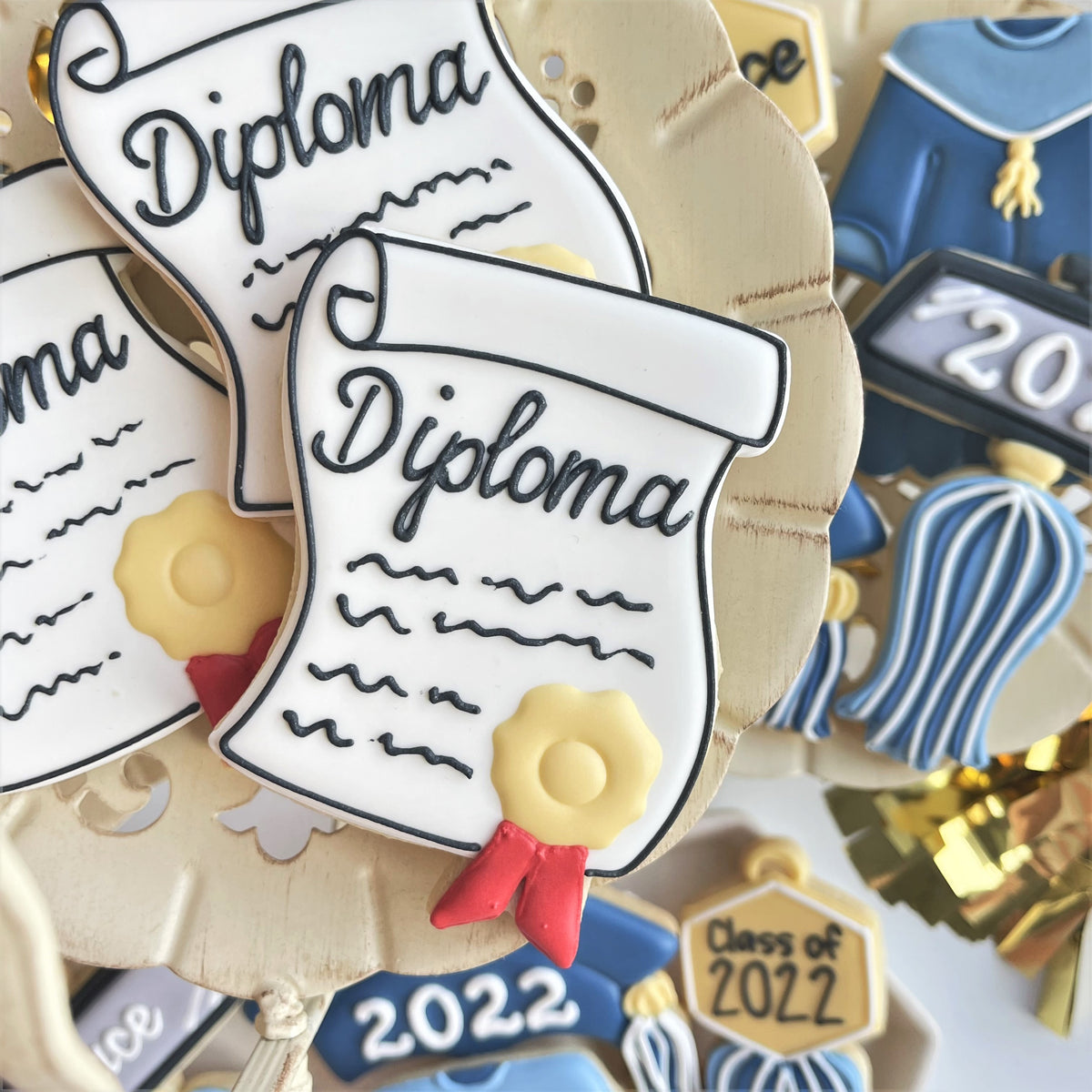 White sugar cookie shaped like a diploma with black script yellow seal and red ribbon made with diploma with seal cookie cutter