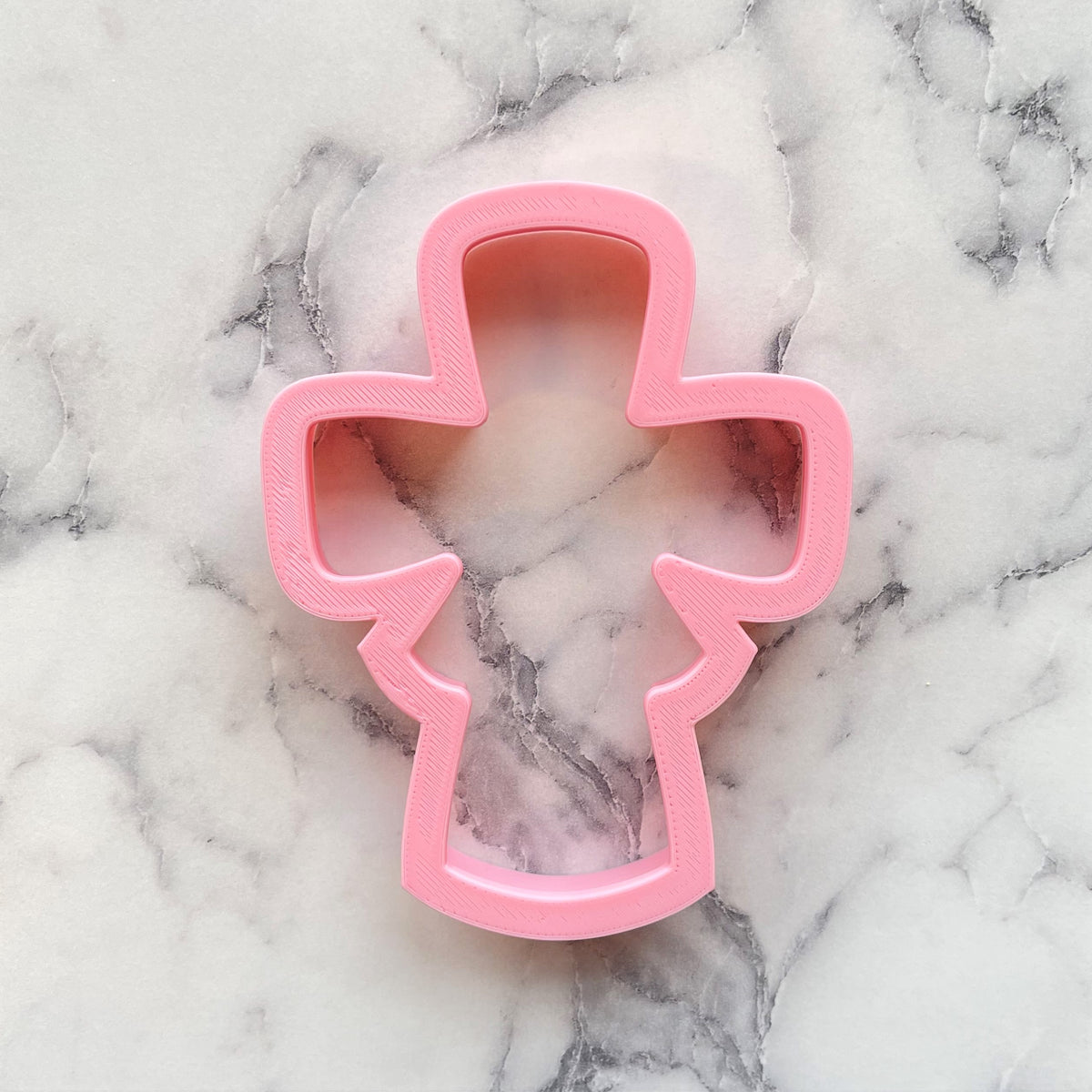 Pink plastic Easter cross cookie cutter with rounded edges and central cutout for festive baking use