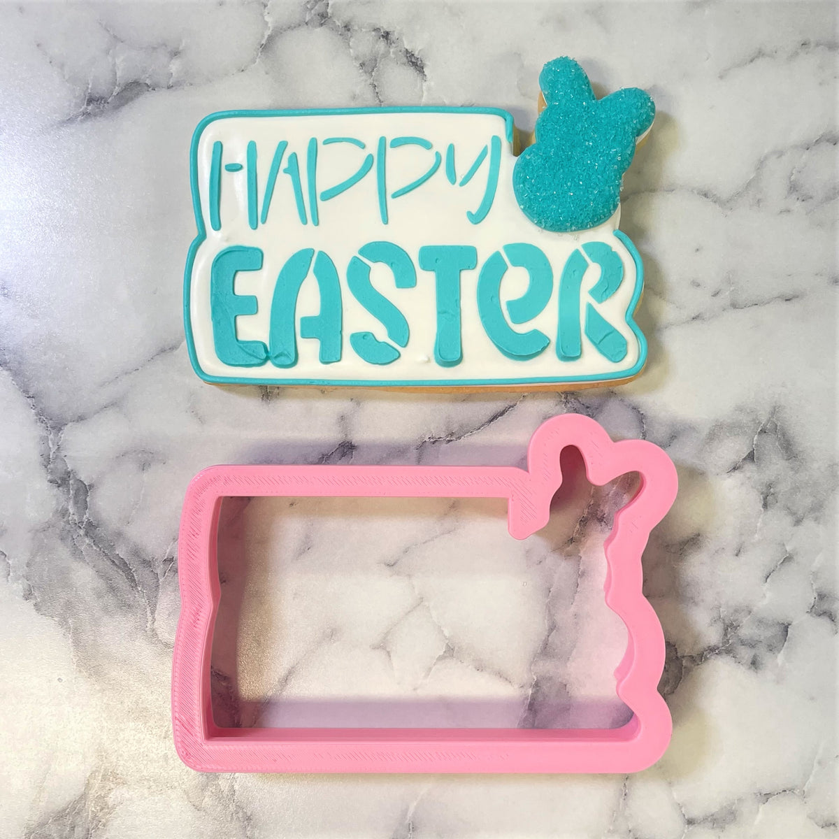Pink plastic happy easter plaque cookie cutter with stencil shaped like a bunny and teal icing decoration