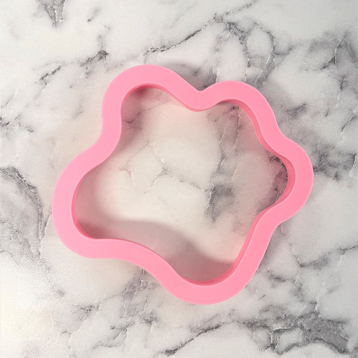 Pink silicone fried egg cookie cutter mold shaped like a paw with a smooth flexible surface