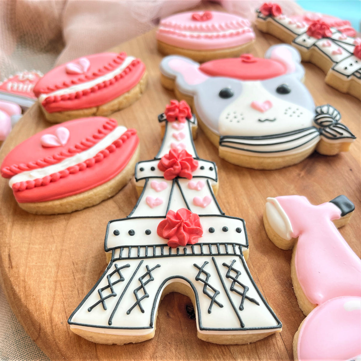 White and black iced eiffel tower cookie decorated with pink frosting flowers from paris valentine’s cookie class recording
